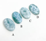 Close up of ocean blue larimar cabochon showing natural white wave patterns and polished gemstone surface