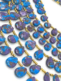 Blue and purple copper turquoise teardrop beads with polished surfaces and top-drilled holes shown on white background