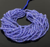 Faceted natural tanzanite rondelle bead strands for jewelry making displayed against a dark background