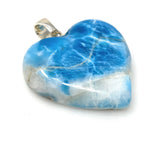 Close up of blue larimar heart gemstone showing ocean wave patterns and natural white marbling