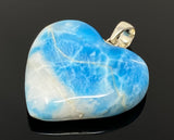 Close up of blue larimar heart gemstone showing ocean wave patterns and natural white marbling from different angle