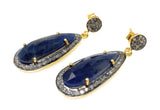 Set of blue sapphire pave diamond earrings arranged on white background, showing side shot of the earrings