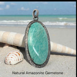 Close up of Amazonite healing crystal Pendant showing polished blue green  oval gemstone and sparkling diamonds around gemstone bezel set in oxidized sterling silver.