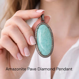 Genuine Peruvian Amazonite Pendant bezel set with genuine diamonds in oxidized sterling silver shown held by woman's hand between thumb and finger.