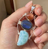 Large larimar labradorite sunstone pendant held in hand showing size and silver craftsmanship