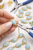 Natural Larimar connectors used in jewelry making on designer workbench with tools and supplies for handmade necklace and bracelet designs
