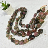 watermelon tourmaline gemstone strand laid flat showing color graduation and natural bi color tourmaline beads