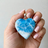 Larimar heart pendant held in hand showing large size and sterling silver setting