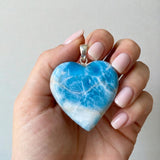 Larimar heart pendant held in hand showing large size and sterling silver setting