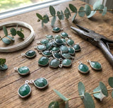 Natural emerald gemstone charms on jewelry designer workbench with tools
 for handmade jewelry making