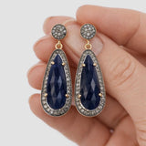 Natural blue sapphire diamond earrings held in  hand, detailed gemstone and silver setting, luxury jewelry close-up