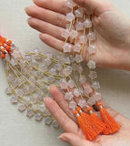 Rose quartz star beads held in hand showing bead size and natural gemstone detail on light colored background.
