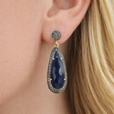 Blue sapphire pave diamond earrings worn on ear by woman, elegant luxury gemstone jewelry, September birthstone earrings