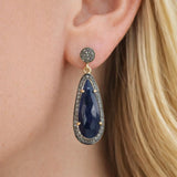 Blue sapphire pave diamond earrings worn on ear by woman, elegant luxury gemstone jewelry, September birthstone earrings