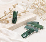 Faceted rectangular green Emerald charm in a double-sided sterling silver bezel with a top loop