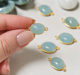 Aquamarine connector held between fingers to demonstrate its scale for handmade jewelry