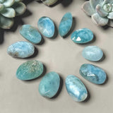 Close-up of untreated Larimar gemstones showing white patterns, aqua tones and natural inclusions