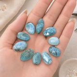 Natural Larimar freeform stones held in a hand to demonstrate scale