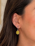 Woman wearing yellow sapphire dangle earrings with gray black rhodium and diamond details