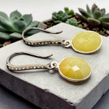 Close-up of faceted golden yellow sapphire gemstones in sterling silver bezel settings
