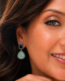 Luxury emerald and blue sapphire gemstone earrings with genuine pavé diamonds styled on a model for an elegant look.