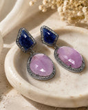 Natural pink sapphire and blue sapphire pave diamond earrings displayed on neutral beige background
