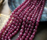 Multiple strands of Pink Sapphire beads arranged together for color and size comparison