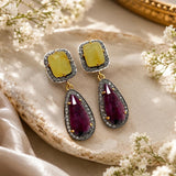 Ruby and yellow sapphire earrings displayed on neutral background