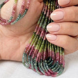 Tourmaline gemstone beads  held in hand to demonstrate bead size and natural colors.