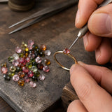 Jeweler setting natural multi-color tourmaline cut stones into a handcrafted ring using professional jewelry-making tools.