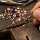 Luxury ring being handcrafted with natural faceted multi-color tourmaline gemstones using traditional jewelry-making techniques.