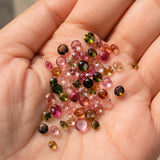Beautiful hand holding natural multi-color faceted tourmaline cut stones, loose gemstones for fine jewelry making and custom designs.