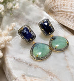 Detailed view of natural emerald and sapphire gemstone earrings showing pavé diamond craftsmanship and dark rhodium finish.