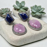 Natural blue sapphire and pink sapphire drop earrings with pave diamond halos displayed with succulent plants