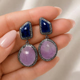 Natural pink and blue sapphire pave diamond drop earrings shown in hand with larger pink sapphire gemstones