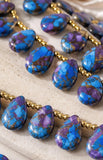 Polished blue and purple Mojave Copper Turquoise beads with distinctive copper matrix patterns.