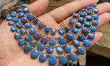 Polished blue and purple Mojave Copper Turquoise beads with distinctive copper matrix pattern shown on hand