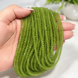 Natural Peridot gemstone beads held in hand showing bead size and vibrant green color.