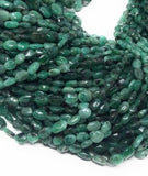 Close-up of genuine emerald gemstone beads highlighting natural color variations and smooth oval shape.