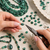 Natural emerald gemstone beads being handcrafted into luxury jewelry using professional jewelry-making tools.