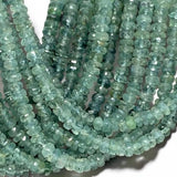 Close up of natural green blue tourmaline faceted rondelle beads showing color variations and gemstone facets