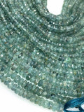 Close up of natural blue green tourmaline beads showing faceted surfaces clarity inclusions and varied gemstone tones