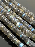 Natural Labradorite faceted heishi beads with blue flash on a black background