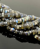 Blue flash Labradorite heishi beads photographed on a dark background