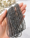 Hand holding shimmer coated Labradorite gemstone bead strands showing size