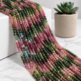 Natural Watermelon Tourmaline round bead strands displayed beside a succulent pot showing pink green and multicolor gemstone tones