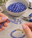 Natural Tanzanite faceted rondelle beads being used with jewelry making tools to create handmade gemstone jewelry.