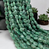 Close-up of natural Emerald beads showing smooth oval shapes, polished finish and lighter to deeper green gemstone tones