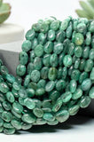 Close-up of natural Emerald smooth oval beads showing polished surfaces, natural inclusions and individual green color variations