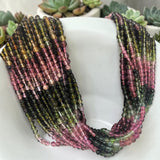 Natural Tourmaline round bead strands displayed around white pot showing watermelon pink green gemstone shades